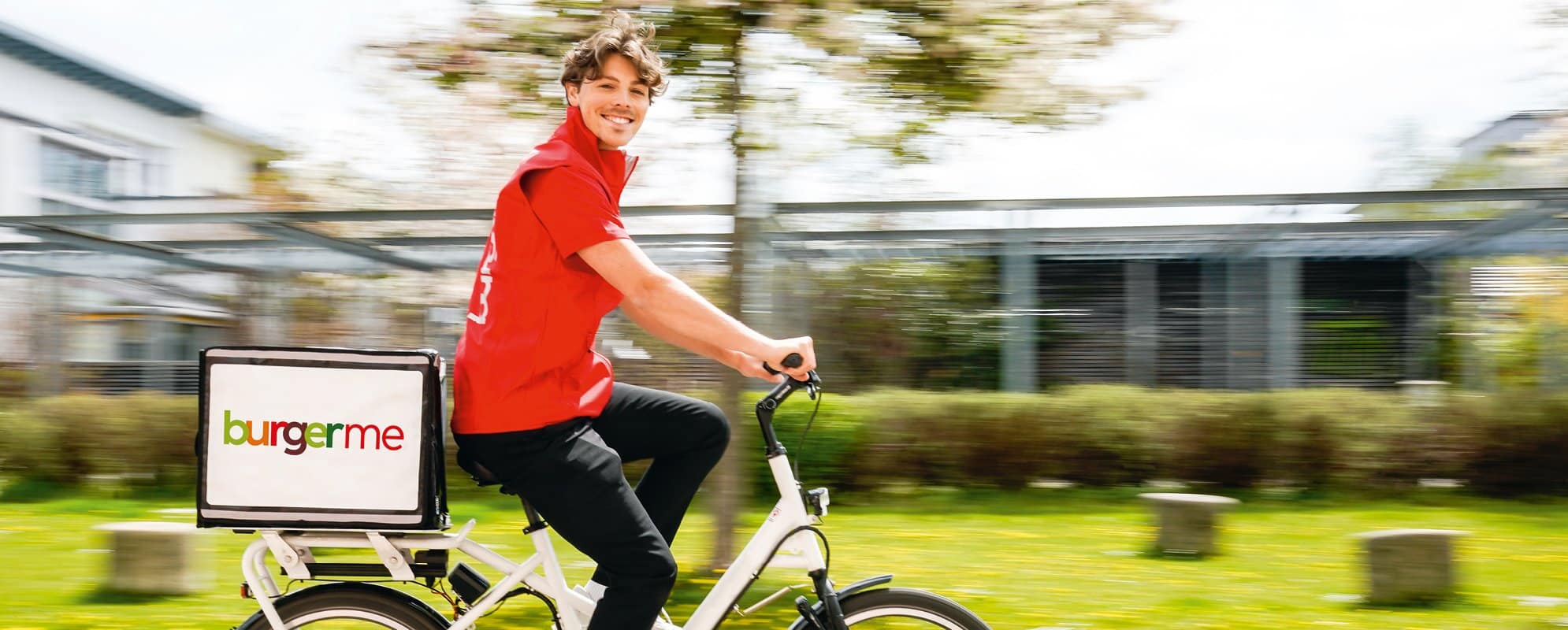 burgerme-Lieferant bringt frische Burger auf dem Fahrrad direkt zu Kunden nach Hause. Schnelle und umweltfreundliche Lieferung.