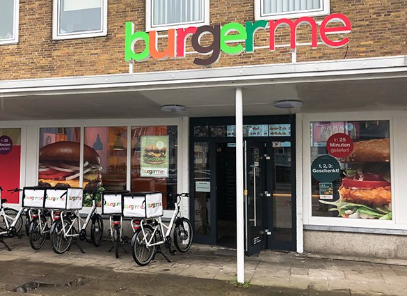 Außenansicht einer Burgerme-Filiale mit Lieferfahrrädern vor dem Eingang.
