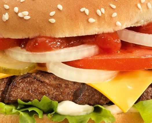 Saftiger Burger mit Käse, Zwiebeln, Tomaten, Essiggurken, Salat und Ketchup im Sesambrötchen von burgerme – der perfekte Genuss!