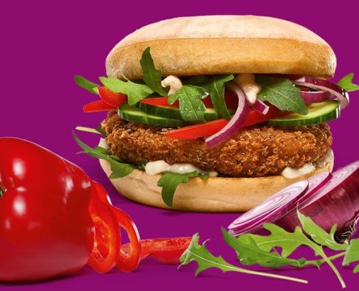 Meatfree Italian Frischer veganer Burger mit Gemüsebeilage, roter Paprika und Zwiebeln von burgerme vor lila Hintergrund.